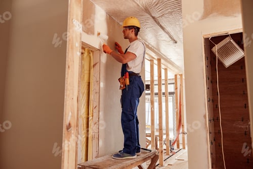 Preview: Male builder painting wall in house under construction