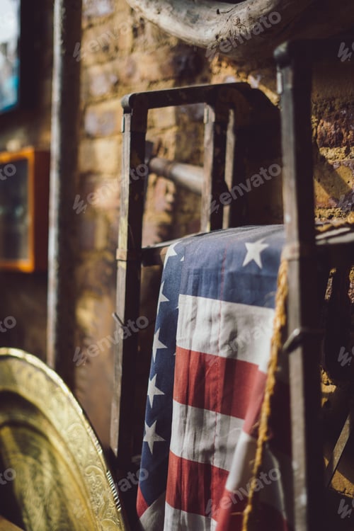 Preview: Vertical shot of the flag of the United States hung on a metal stand in an ancient attic