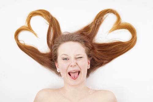 Preview: Young woman with hair forming heart shape and winking while sticking out tongue