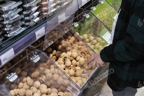 Preview: A customer uses a scoop to select pistachios from a bulk bin at a grocery store. The photo