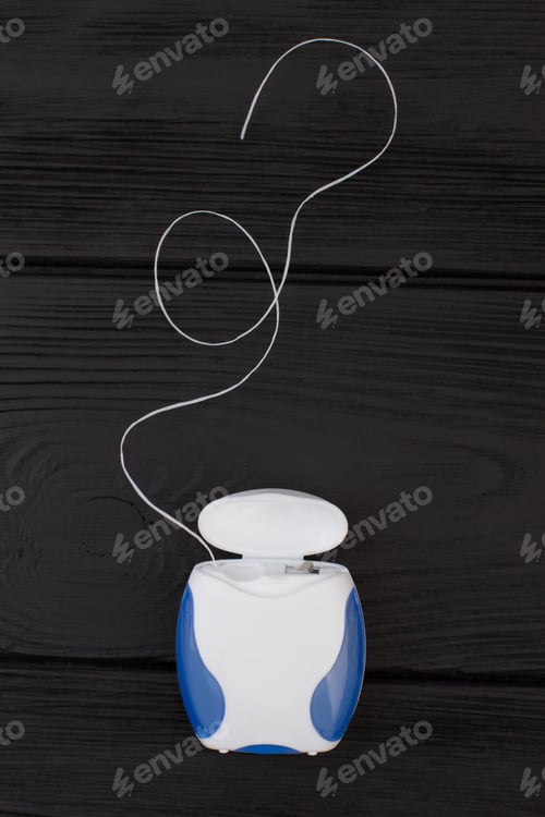 Preview: Dental floss on black wooden background