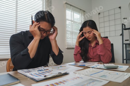 Preview: Stressed business team having headache while examining financial reports in office