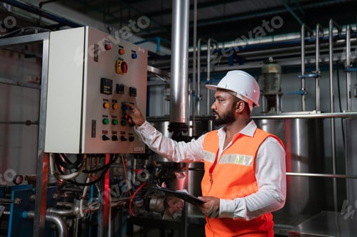 Preview: Engineering man in protective safety uniform working with clipboard at factory.