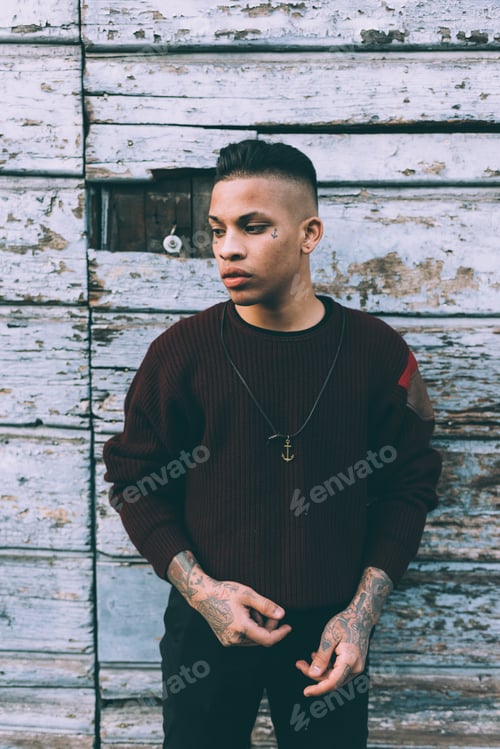 Preview: young hispanic tattoed man outdoor in the city, resolute