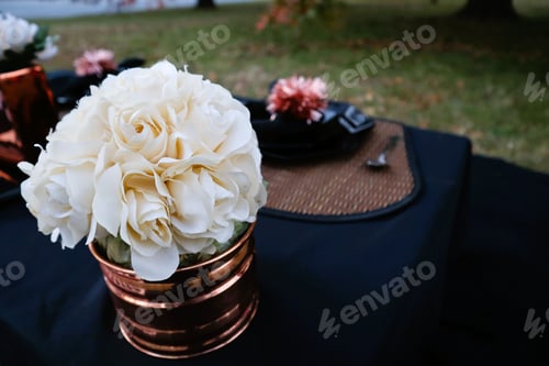 Preview: Copper vase filled with white flowers on a black table in the yard