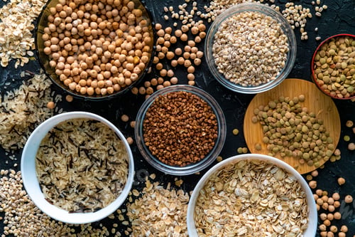 Preview: selection of raw uncooked cereals grains in bulbs with chickpeas oat lentil rice buckwheats