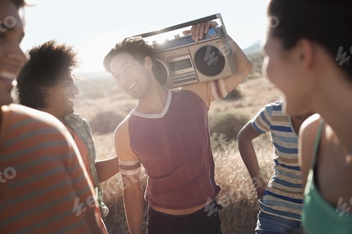 Preview: Group of young people, men and women walking on the open road with a boombox.