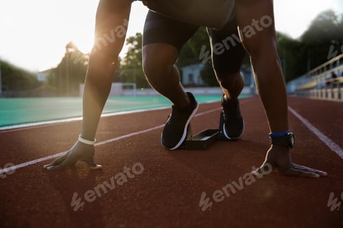 Preview: Cropped image of a young african male sprinter getting ready