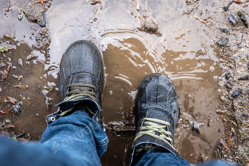 Preview: View from above on pair of trekking shoes in a mud.
