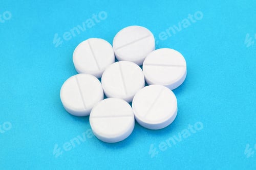 Preview: A few white tablets lie on a bright blue background surface. Background imag