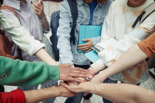 Preview: Group of intercultural teenage students in casualwear making pile of hands