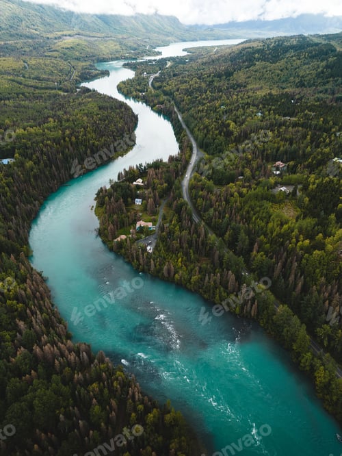 Preview: Vertical aerial view of the Kenai River flowing in a forest surrounded by lush nature in Alaska