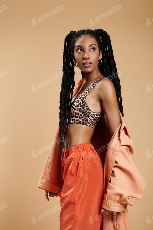 Preview: A vibrant young woman showcases stylish confidence against a warm background in an urban setting