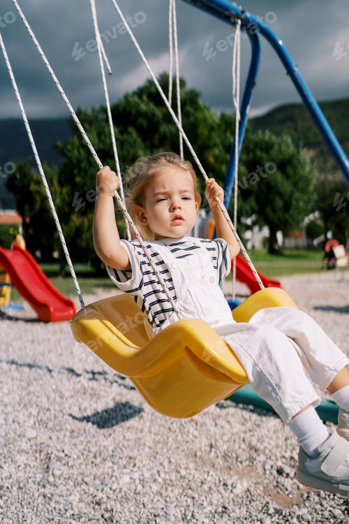 Preview: Little girl swings on a rope swing at the playground