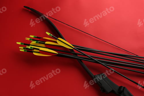 Preview: Black bow and set of arrows on red background, flat lay. Archery sports equipment