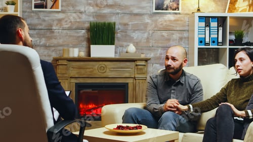 Preview: Young couple holding hands sitting on couch