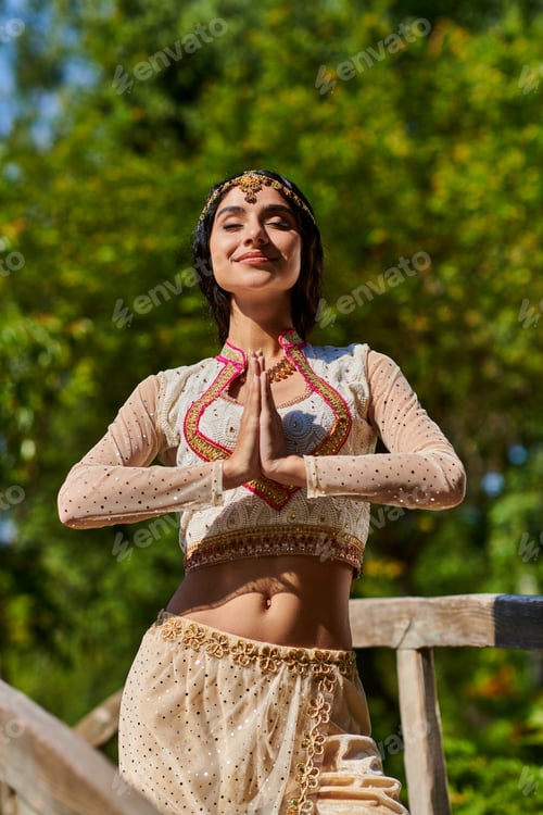 Preview: pleased authentic style woman posing with praying hands in park during summer outing