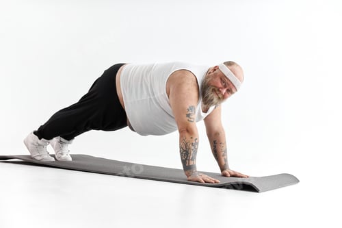 Preview: Sporty fat man with beard and tattoos is doing yoga