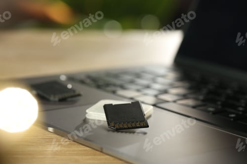 Preview: SD memory cards, holder and laptop on wooden table, closeup