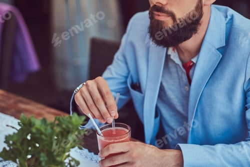 Preview: Fashionable bearded male with a stylish haircut sitting in a cafe outdoors.