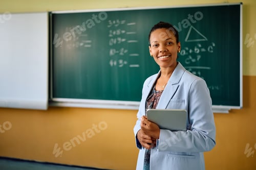 Preview: Happy black female teacher in the classroom looking at camera.