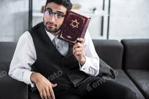 Preview: handsome jewish man in glasses holding tanakh and looking at camera