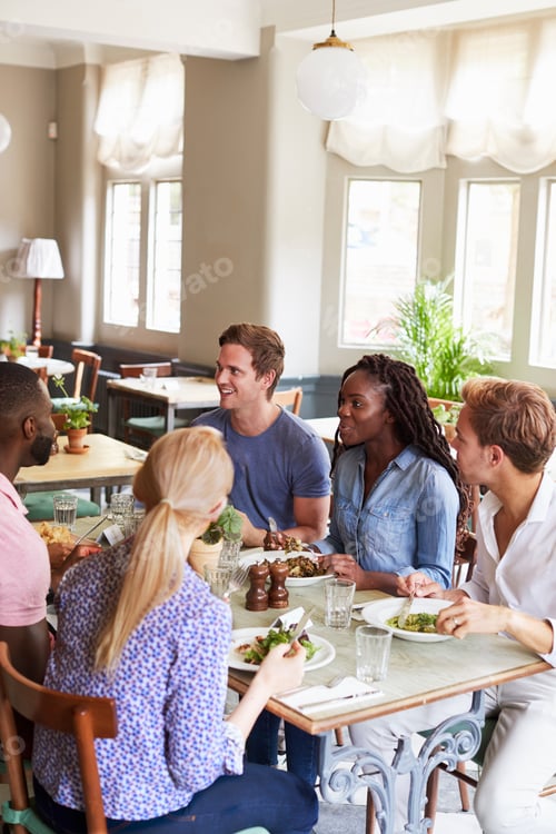 Preview: Group Of Friends Sitting At Table In Restaurant Enjoying Meal Together
