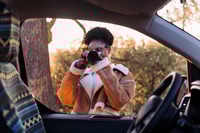 Preview: woman taking photos with camera during a road trip