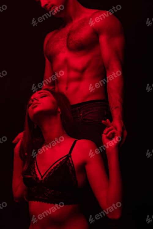 Preview: partial view of passionate undressed sexy man touching woman in red light isolated on black