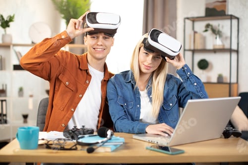 Preview: Young couple using VR headset and laptop for playing games