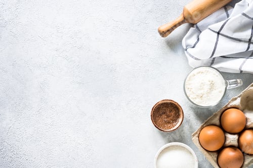 Preview: Baking background ingredients. Flour, sugar, eggs and rolling pin at light stone table.