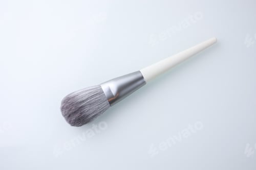 Preview: a brush for applying powder in make-up lies on a white glass table.