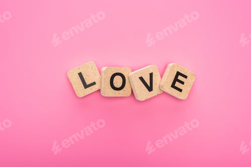 Preview: top view of love lettering on wooden cubes isolated on pink