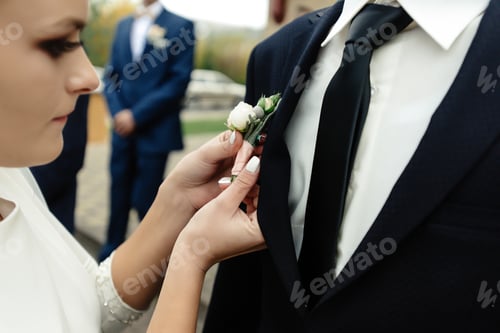 Preview: stylish gorgeous bride putting on boutonniere on elegant groom at church ceremony