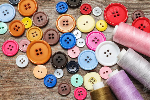 Preview: Colorful buttons and threads on wooden background, top view. Tailoring equipment
