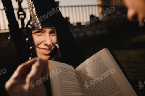 Preview: Reflection of smiling woman with book near fence