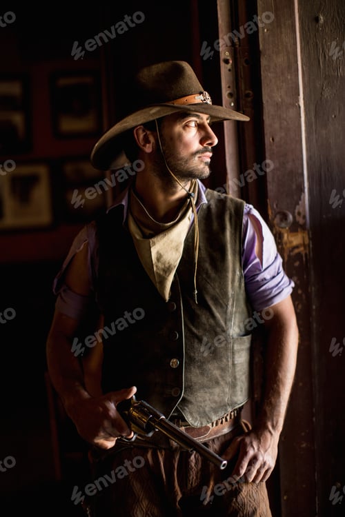 Preview: Portrait of cowboy holding handgun in doorway on wild west film set, Fort Bravo, Tabernas, Almeria,