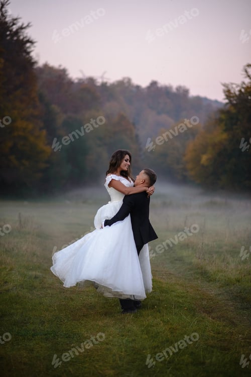 Preview: The groom circles the bride in his arms. Against the backdrop of fog and an autumn park.