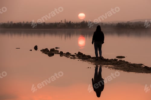 Preview: Unrecognised person standing and enjoying the sunset at a lake. Larnaca Cyprus