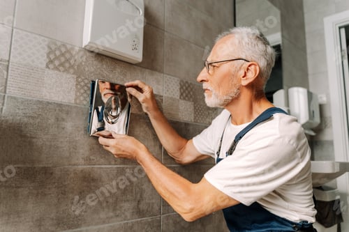 Preview: Plumber installing toilet flush button in public bathroom