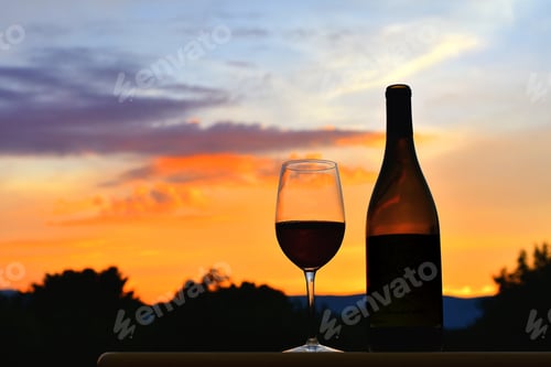 Preview: Wine bottle and glass silhouette against a sunset over the mountains