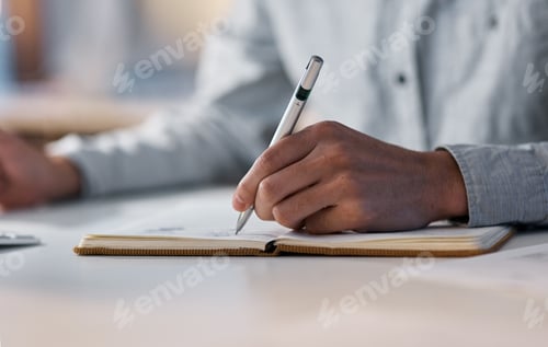 Preview: Shot of an unrecognisable businessman writing in a notebook during a late night at work