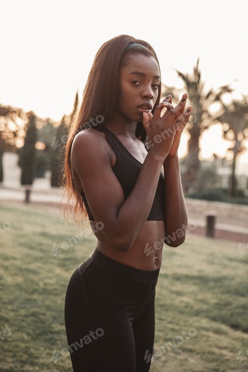 Preview: A black girl dressed in sportswear poses in front of the camera at sunset.