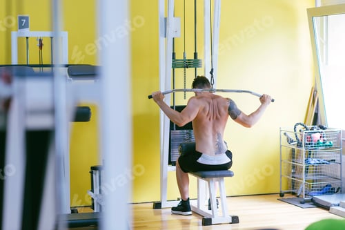 Preview: Fit man on lat pull down machine at the health club. Work out on Pull down Weight Machine