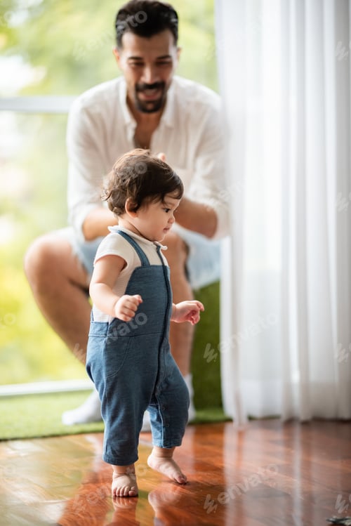Preview: cute toddler little child family concept, baby learning to walk with father and mother to help care