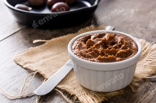 Preview: Chestnut cream in ramekin with roasted chestnuts in a pan on rustic wooden table