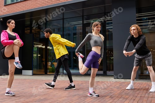 Preview: Dynamic group engages in warm up exercises in urban fitness space during the afternoon