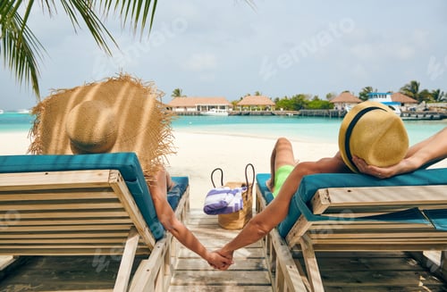 Preview: Couple at beach on wooden sun bed loungers