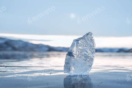 Preview: A transparent icicle on the frozen surface of Lake Baikal in winter against the sky. Close-up.