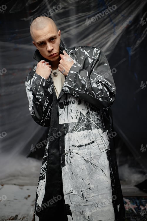 Preview: Portrait of Professional Male Fashion Artist in Custom Coat Painted with White Print in Studio